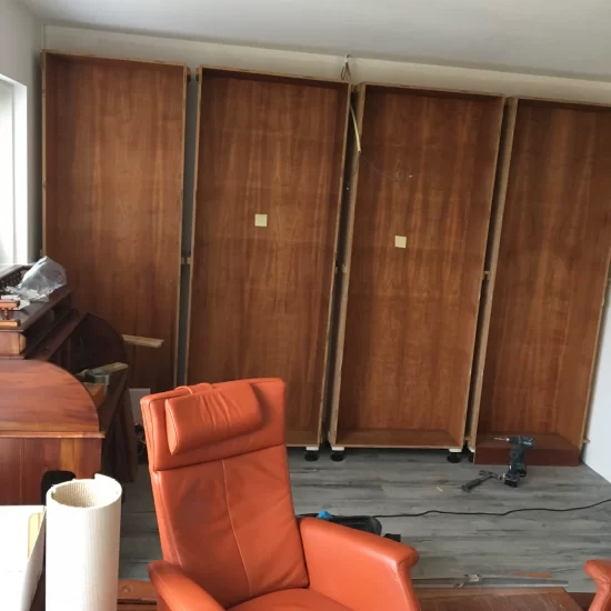 De montage van een boekenkast met een klassiek uiterlijk van donker hout, bestaande uit vier delen.