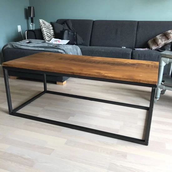 Een rechthoekige lounge tafel met een donkerbruin houten blad en een zwart stalen frame.