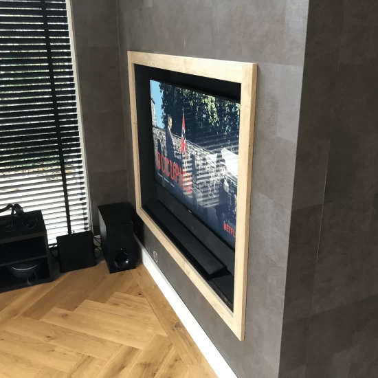 Een televisiekast gemonteerd in de muur, met een rand van licht gekleurd hout.